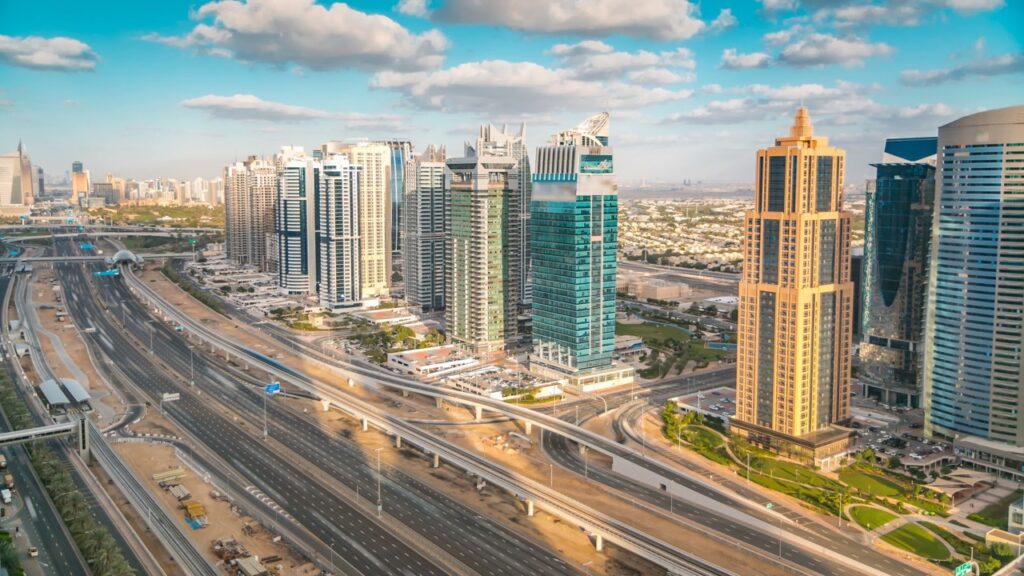 Aerial view of Dubai marina skyscrapers and Jumeirah lakes towers timelapse with traffic on sheikh zayed road. Sunset time with cloudy blue sky