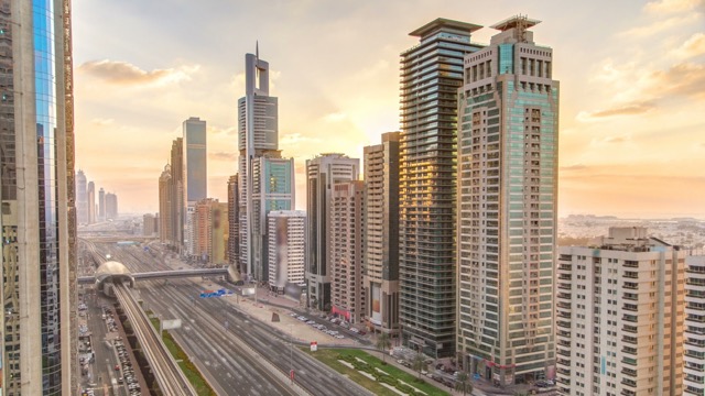 Downtown Dubai towers in the evening timelapse. Aerial view of Sheikh Zayed road with skyscrapers at sunset. Traffic on the road and metro line. Beautiful orange sky